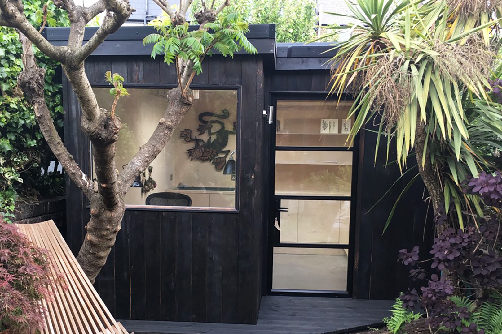 Black clad garden studio with a Plywood interior nestled amongst the trees
