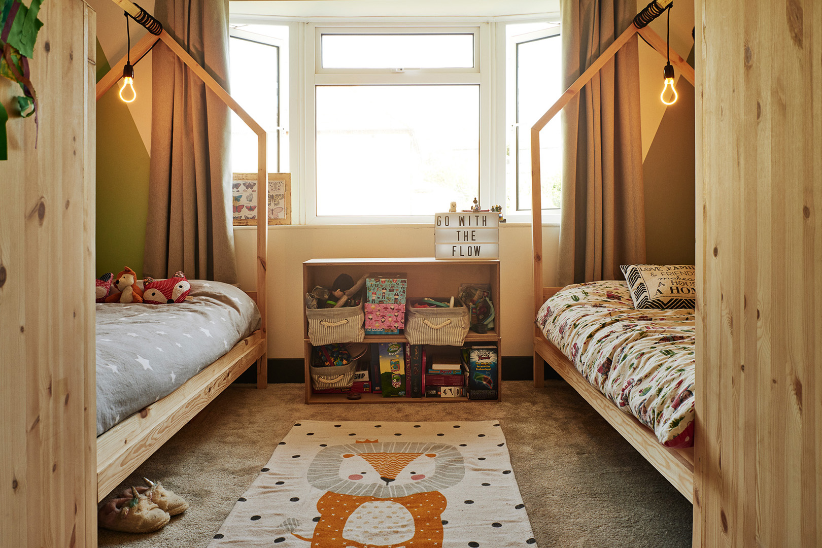 A pair of pine children's house beds in a carpeted room with a cute lion rug