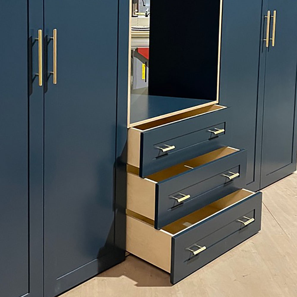 close up of drawers on a large navy blue and brass bedroom furniture unit
