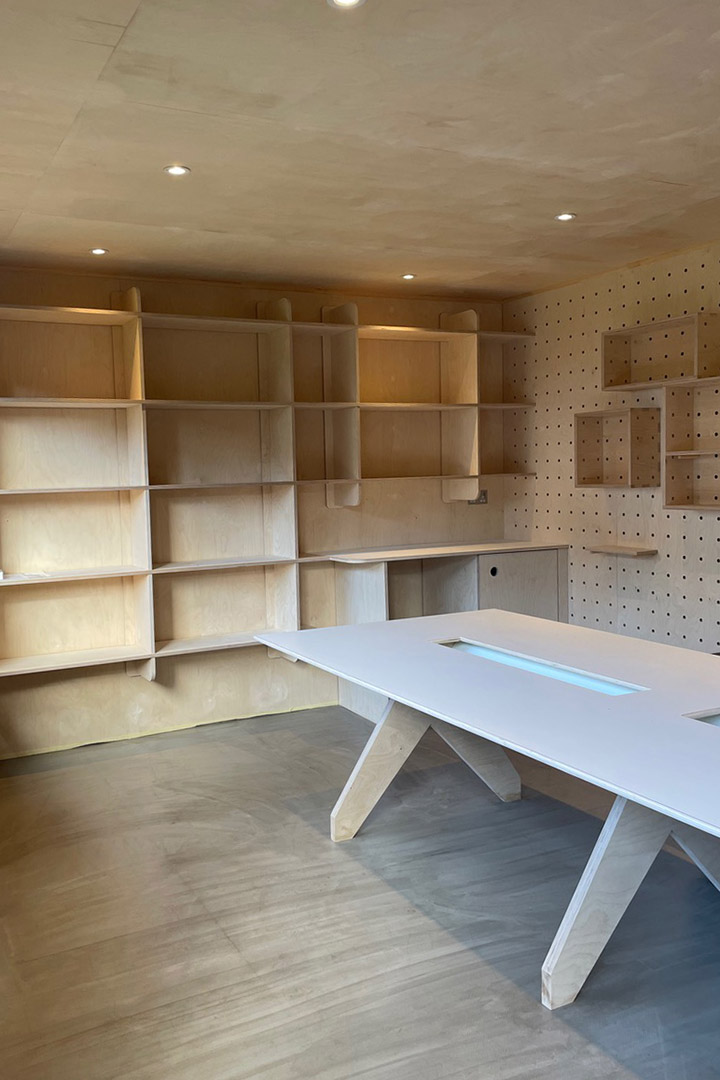 interior view of the garden office with a large Plywood desk, full wall Plywood shelving and pegboard