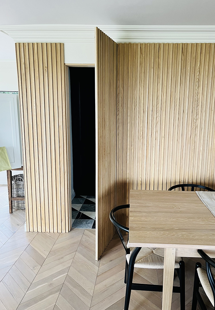 secret door and wall clad in oak slats in the dining room of a luxury home
