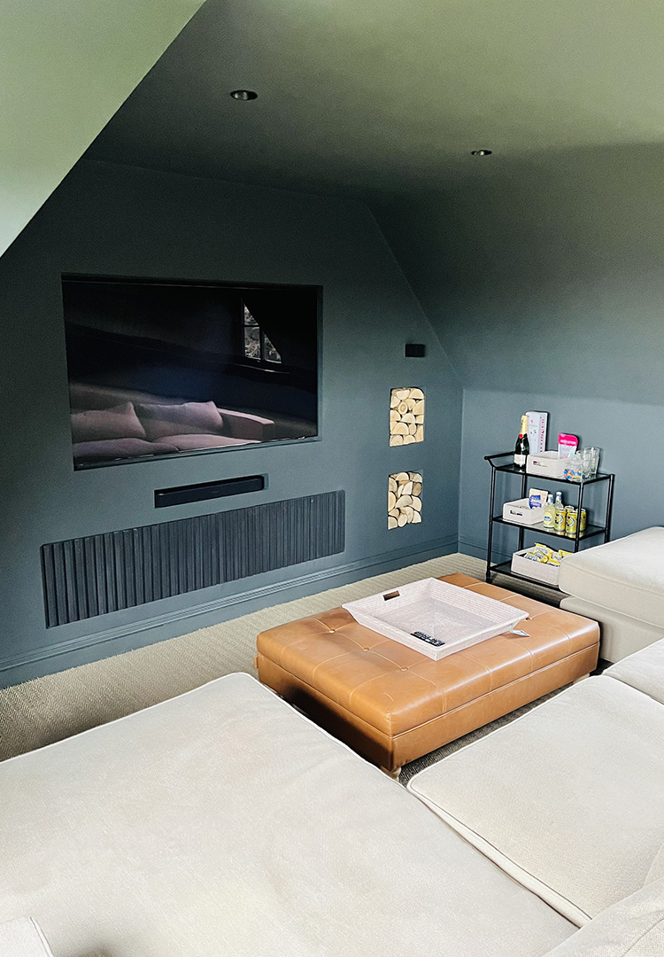 small hidden hifi unit set in the wall below a TV with dark stained oak slats on the front panel