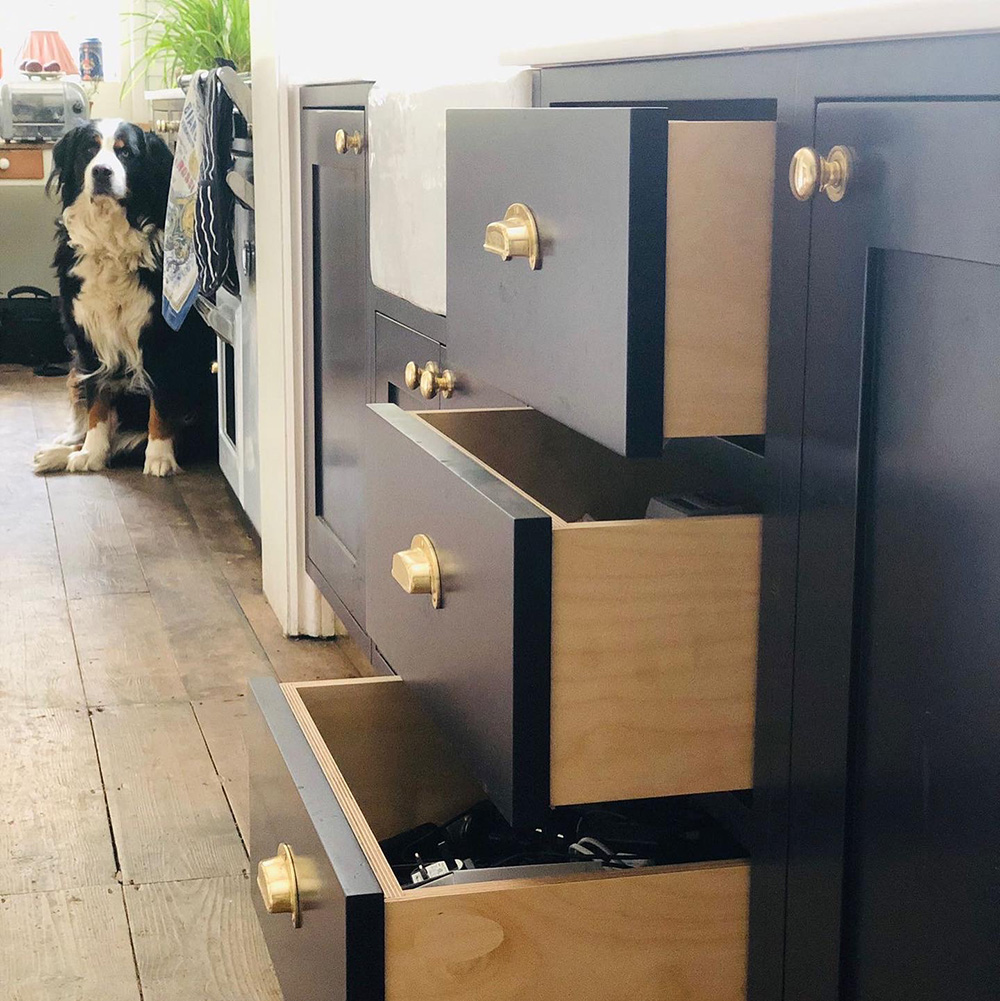 close up view of the in frame shaker style drawers that are painted dark blue with brass cup handles