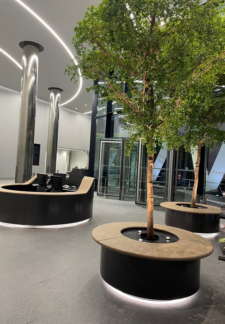 view of the lobby area in the gherkin london with both planters, trees and the reception desks