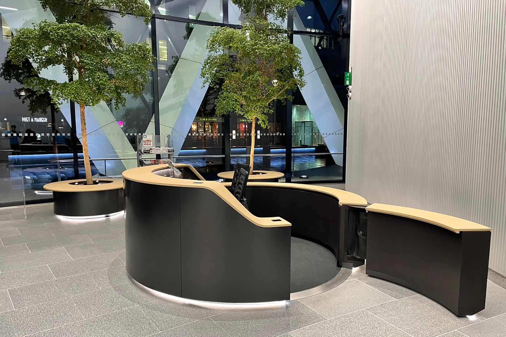 Circular black metal reception desks at the gherkin london with planters in the background