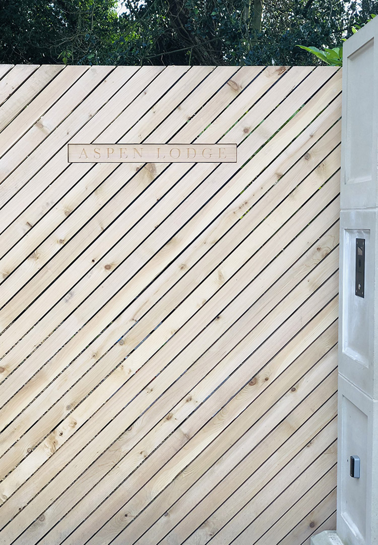 Engraved letterbox on an automated gate clad with diagonal slats of Cedar
