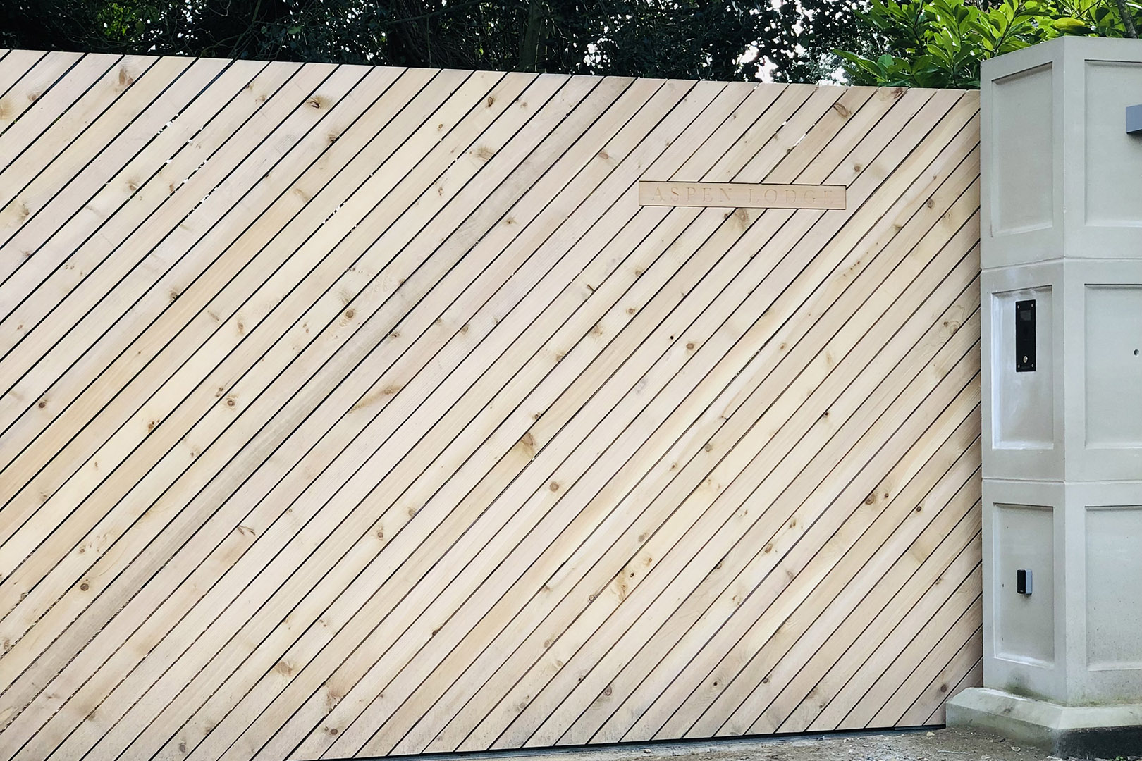 A sliding automated gate clad with diagonal slats of Cedar