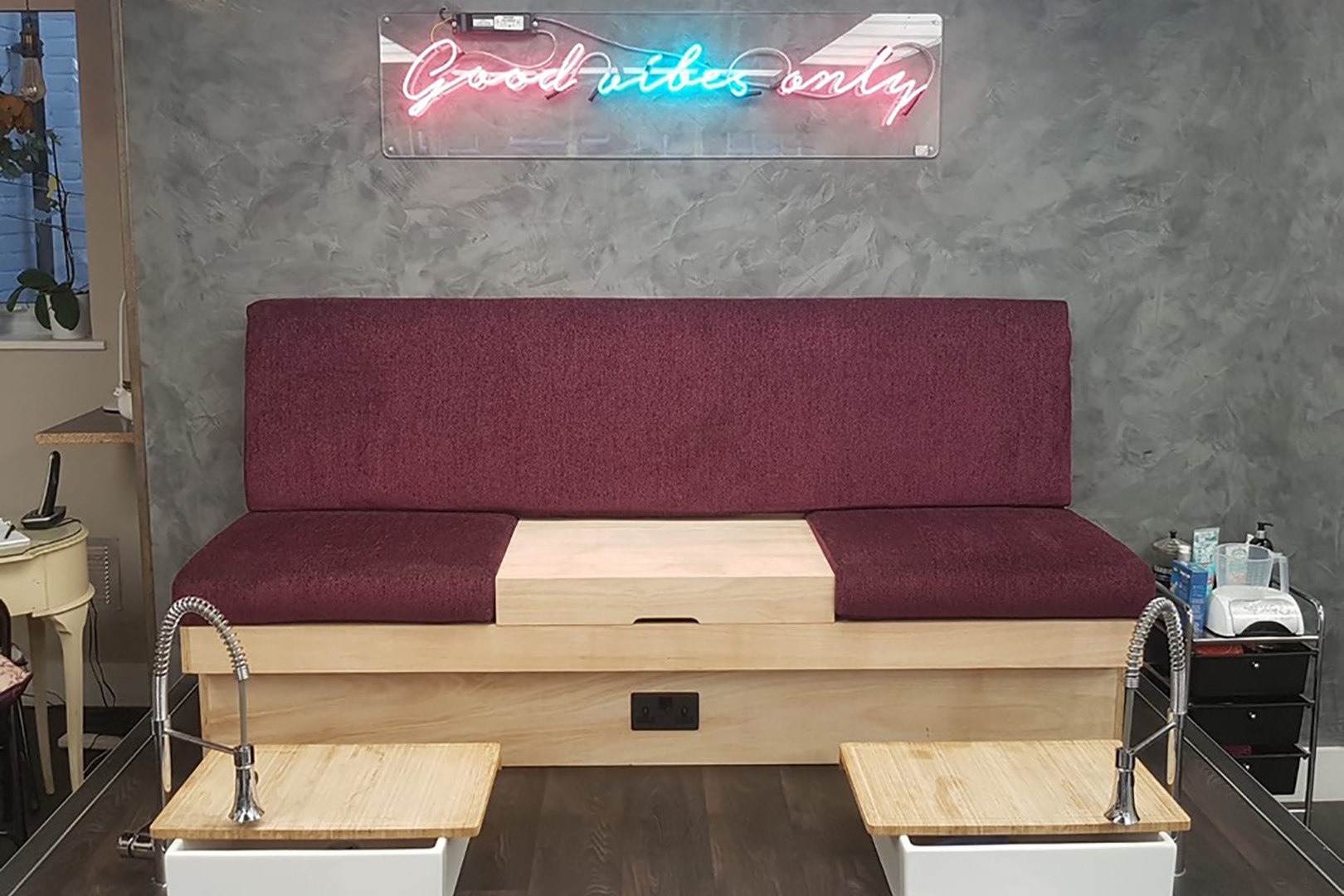 A maroon and wood beauty treatment sofa for pedicures