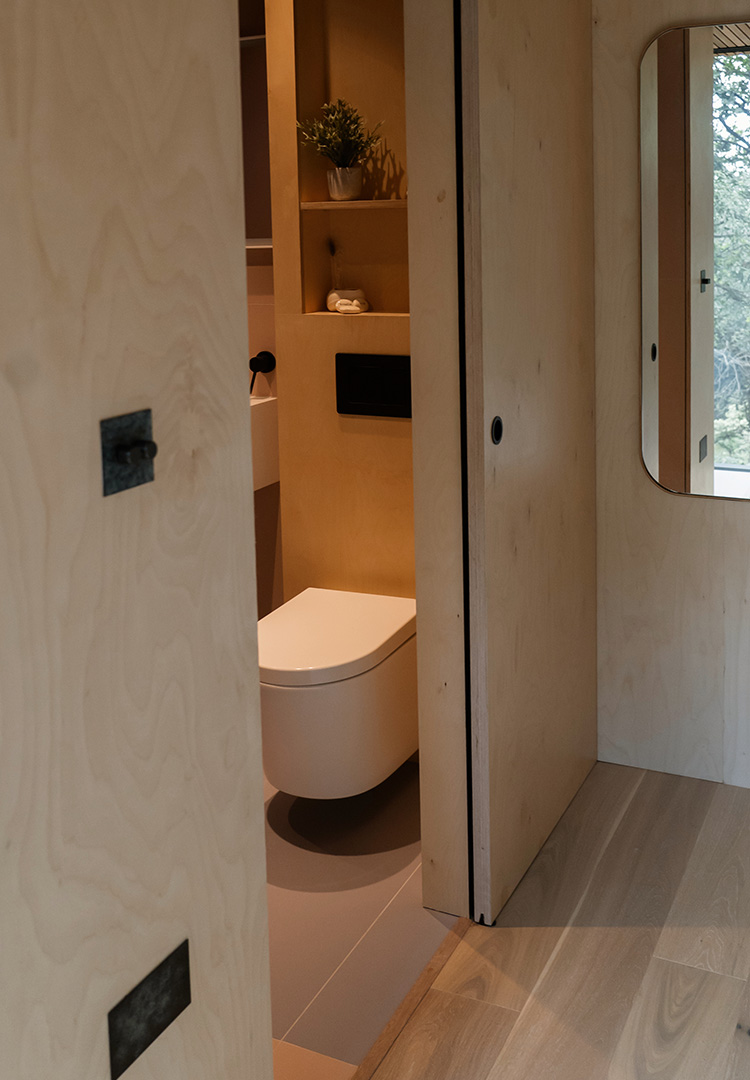 peaking view through plywood sliding doors into the modern toilet at looking glass lodge