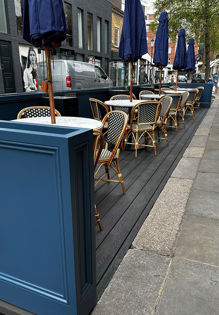 A view of the tables, chairs and parasols on the decked outdoor seating area of Daphne's restaurant in London Kensington